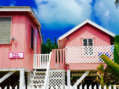 a pink house with a sign that reads pinkason at Hummingbirds Cabins in Caye Caulker