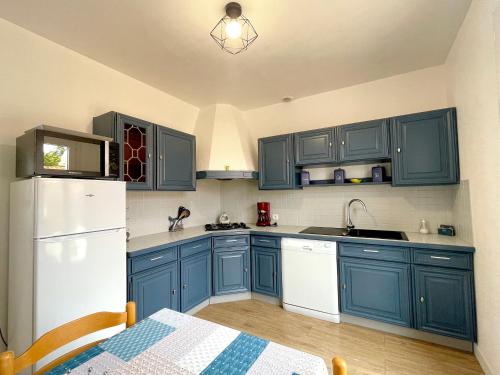 La cuisine est équipée de placards bleus et d'un réfrigérateur blanc. dans l'établissement Maison rénovée 3 ch. proche mer, animaux admis, terrasse et parking - FR-1-231-290, à Bretignolles-sur-Mer