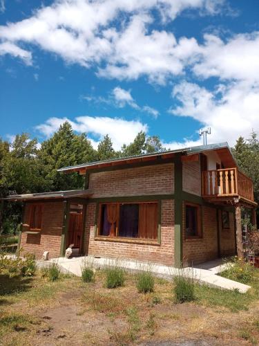 a small brick house with a balcony on top at chacra EL PORTAL in Epuyén