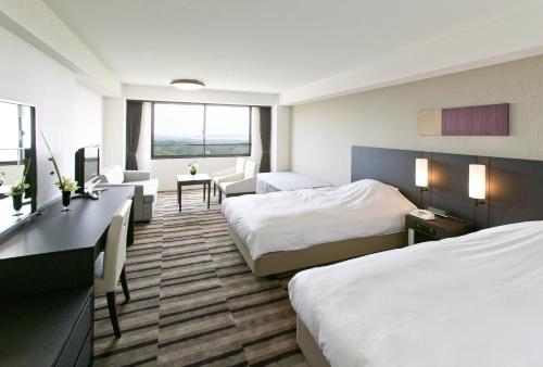 a hotel room with two beds and a desk at Grand Mercure Ise-shima Resort & Spa in Shima