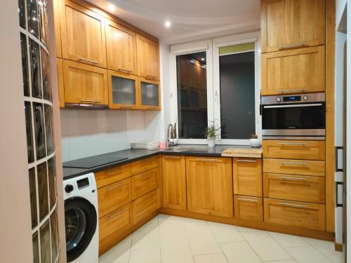 a kitchen with wooden cabinets and a washer and dryer at Apartament przy Operze in Białystok