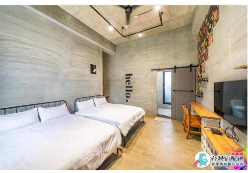 a bedroom with two beds and a table and a tv at 隱月民宿 in Hengchun South Gate