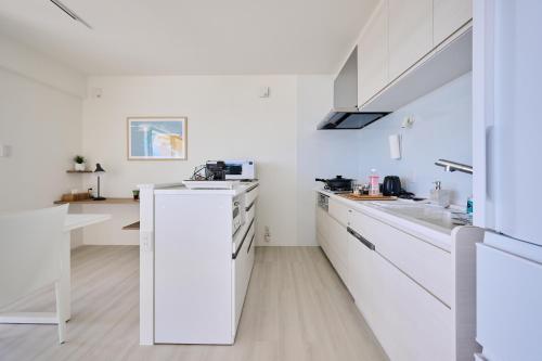 a white kitchen with white cabinets and a sink at 青風 Aokaji 古宇利島のプール付き一棟ヴィラ in Kouri