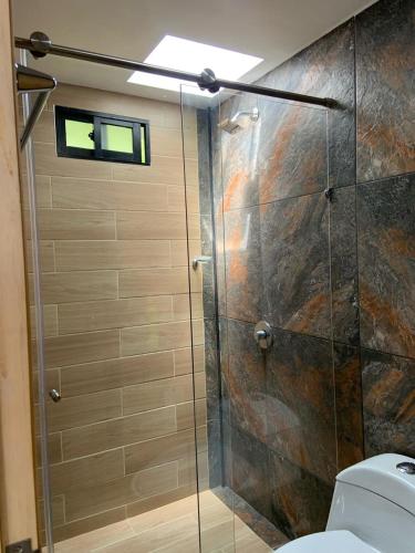 La salle de bains est pourvue d'une douche avec une porte en verre. dans l'établissement Jacaranda Glamping, à El Peñol