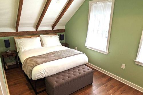 バッファローにあるWalkable Elmwood Cottage, No Chores 2Bath 2BR 2Carの緑の壁のベッドルーム1室、オットマン付きのベッド1台