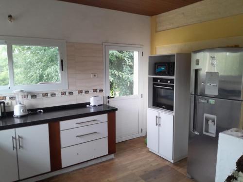 uma cozinha com armários brancos e um frigorífico de aço inoxidável em Casa de Campo La Querencia em Mercedes
