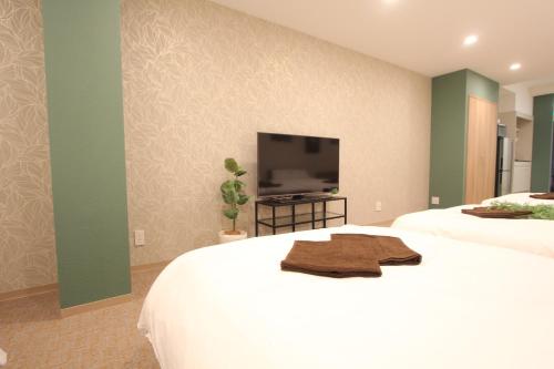 a bedroom with two beds and a flat screen tv at LUANAHOTEL IN KOUENJI in Tokyo