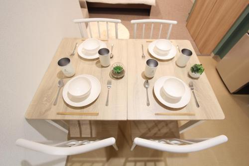 a wooden table with plates and utensils on it at LUANAHOTEL IN KOUENJI in Tokyo