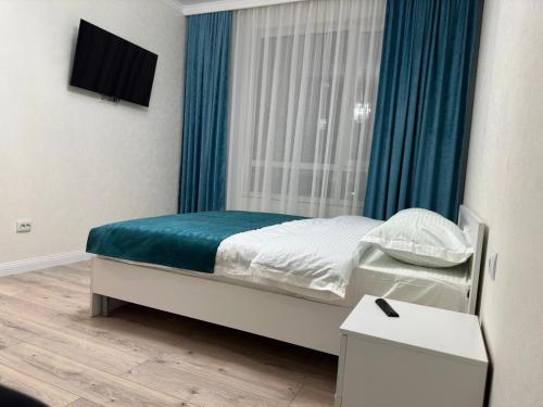 sypialnia z łóżkiem i oknem z niebieskimi zasłonami w obiekcie Apartaments COSTA ЖК Тандау w mieście Astana