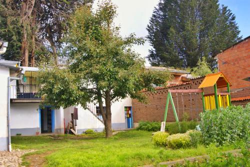 une maison avec un arbre dans la cour dans l'établissement Hostal Ancohuma, à Peñas