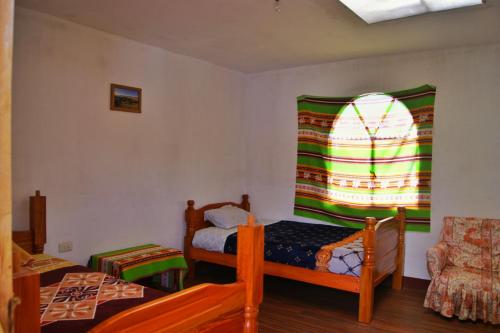 a small room with two beds and a window at Hostal Ancohuma in Peñas