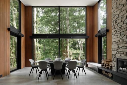 a dining room with a table and chairs and large windows at Villa El Cielo Hakuba in Hakuba