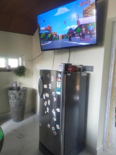 a tv on a wall with a refrigerator in a room at The two bedroom homestay in Madikeri