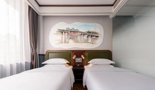two beds in a room with a painting on the wall at Nost algia S Hotel Chengdu KuanZhai Alley & Renmin Park 时光漫步S酒店 成都宽窄巷子人民公园地铁站店 Free fresh ground coffee,Free laundry service in Chengdu