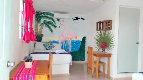 a room with a bedroom with a flamingo painting on the wall at HOTEL LAS COLORADAS in Yuluc