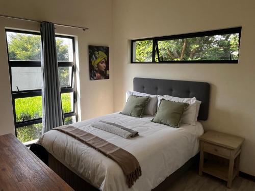 a bedroom with a large bed with two windows at Jackal Creek Golf Estate in Roodepoort