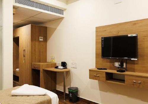 a room with a tv on a wall with a bed at V V Grand in Chennai