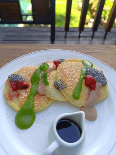 a plate of pancakes with fruit and a tablespoon of syrup at Paripadi Private Villa and Sanctuary in Canggu
