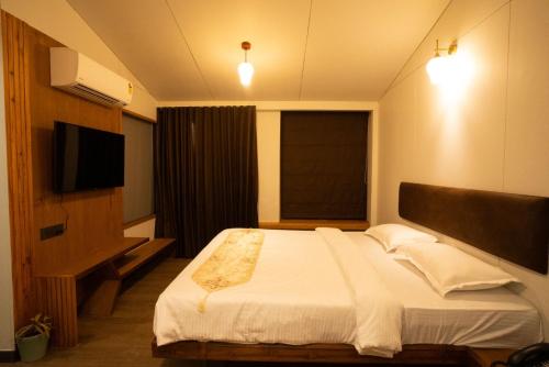 a bedroom with a large bed and a television at Bliss Nirvana Resort in Lonavala