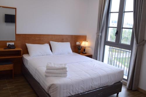 um quarto com uma cama branca e toalhas em Sunrise Hotel em Phu Quoc