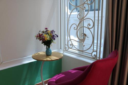 un vase de fleurs assis sur une table à côté d'une fenêtre dans l'établissement Adventure Hotel, à Hô-Chi-Minh-Ville