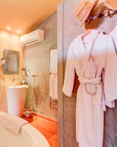 La salle de bains est pourvue d'un peignoir blanc accroché au mur. dans l'établissement Mas de Provence en Riviera, à La Roquette-sur-Var