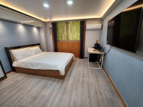 a bedroom with a bed and a flat screen tv at Yuna Hotel by Merciel in Yeongcheon