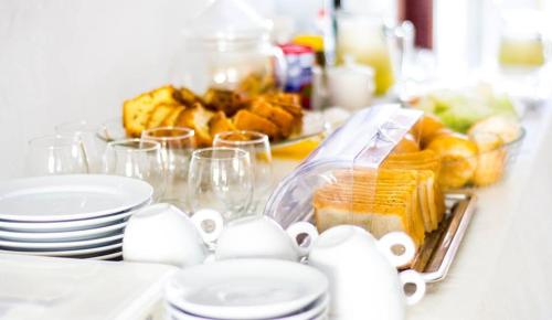 une table avec des assiettes et des tasses et une assiette de nourriture dans l'établissement Sol Hostel & Pousada Maragogi, à Maragogi