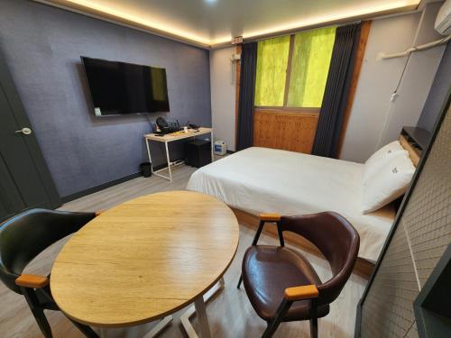 a hotel room with a table and a bed at Yuna Hotel by Merciel in Yeongcheon