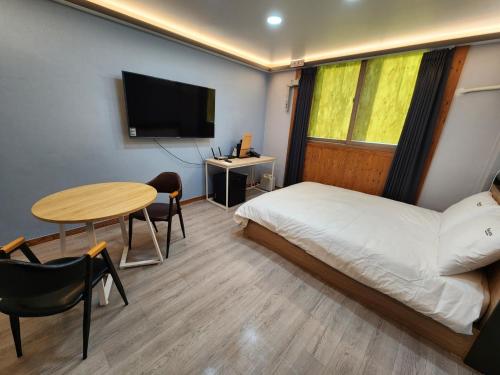 a bedroom with a bed and a table and a tv at Yuna Hotel by Merciel in Yeongcheon