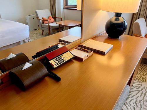a desk in a hotel room with a bed and a table with a lamp at Shima Kanko Hotel The Classic in Shima