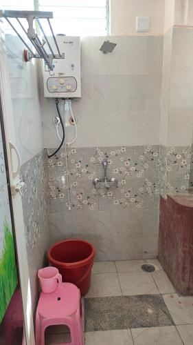 baño con ducha con cubo rojo en Adhvan home stay, en Mysore