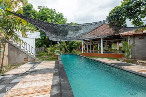 a swimming pool in front of a house with a net over it at Biorock Homestay Pemuteran in Pemuteran