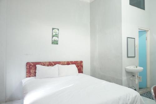 a white bed with a red headboard in a bedroom at Hotel O Pondok Bintang in Kendari