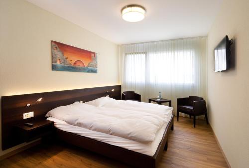 a bedroom with a bed and two chairs and a window at Hôtel Glanis in Gland