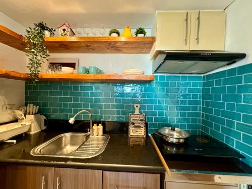 a kitchen with a sink and a blue tiled wall at 2br Golfcourse view near airport in Manila