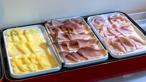 four plastic containers filled with different types of meat and cheese at Hotel Cortaccia Sanvitale in Sala Baganza