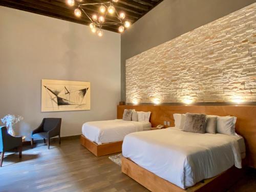 um quarto com 2 camas e uma parede de tijolos em Hotel Plaza D Armas em Querétaro