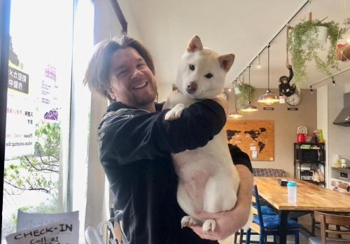 Ein Mann, der einen weißen Hund in den Armen hält. in der Unterkunft Guest House Matsu in Osaka