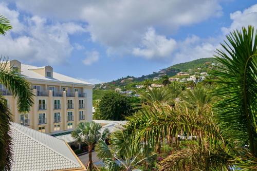 a building with palm trees and a mountain in the background at The Westin St Thomas Beach Resort & Spa in Frydendal