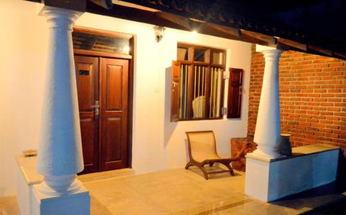 Zimmer mit zwei Säulen, einem Stuhl und einer Tür in der Unterkunft Lihini Scandic Eco Village in Habarana
