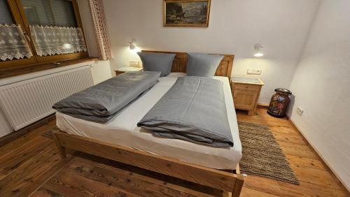a large bed in a room with wooden floors at Steingaden-Urspring Ferienwohnung Bergzeit im Fuchsbau in Steingaden