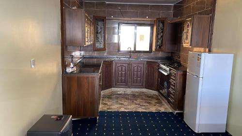 a kitchen with wooden cabinets and a white refrigerator at furnished apartments for rent in Irbid