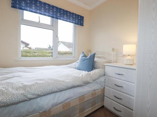 a bedroom with a bed with a dresser and a window at Summer Breeze in Padstow