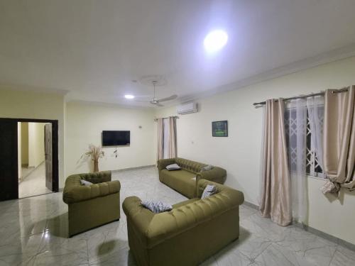 a living room with two couches and a tv at B's Classic and Cozy Apartments in Cape Coast