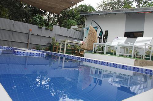 einen Pool mit weißen Stühlen und ein Haus in der Unterkunft Aurora's Place Private Pool 