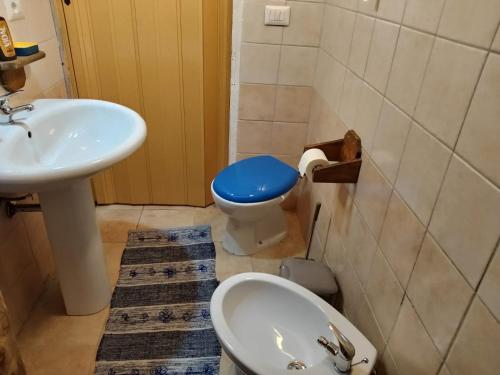 a bathroom with a sink and a toilet with a blue lid at Casa vacanza Su Niu in Iglesias