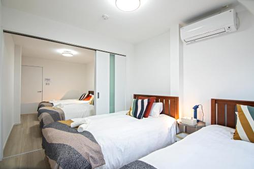 a room with three beds and a mirror at - UMI-Haven 福島 - 隣駅5LDK戸建 in Osaka