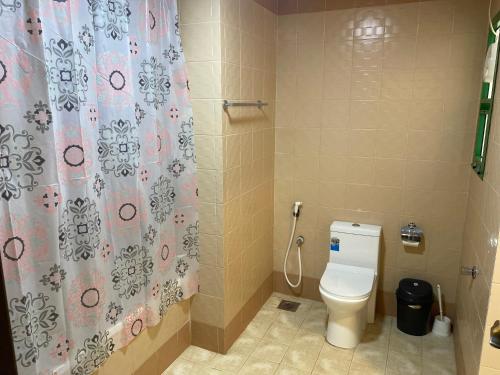 a bathroom with a toilet and a shower curtain at Rest-Inn Furnished Apartments ريست-ان للشقق المفروشة in Muscat