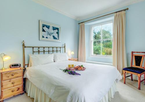 a bedroom with a bed with a plate of food on it at Buckland House in Slapton